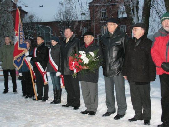 Biało-czerwone kwiaty pod pomnikiem wieszcza